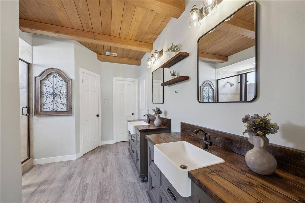 The ensuite bathroom boasts upgraded cabinetry, modern lighting, framed mirrors, and dual farmhouse sinks in spacious vanities for elegance and functionality.