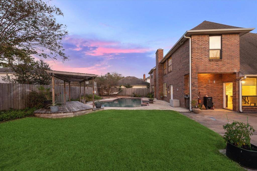 The covered patio is perfect for relaxing or dining al fresco, while a pergola-covered deck adds charm and shade. Lush grass and multiple patios provide ample space for lounging, grilling, and entertaining.