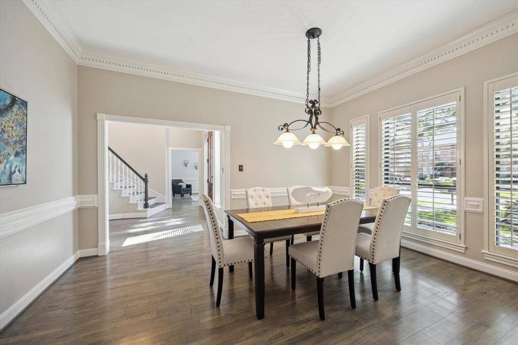 This spacious dining area fits a large table for gatherings, with a perfect wall for a china hutch or decor. An elegant chandelier adds sophistication and warmth.