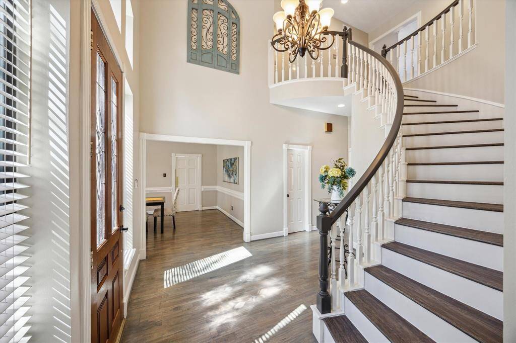 Enter this stunning home through a soaring foyer with gleaming NEWLY REFINISHED floors, a graceful chandelier, and a curved staircase. Large windows flood the space with natural light, creating a warm, inviting ambiance.