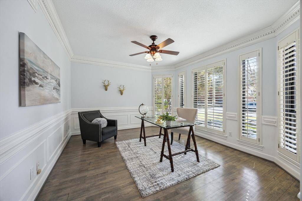 This versatile first-floor room can be a home office or formal living space, featuring wood floors, plantation-shuttered windows, high ceilings, and elegant moldings.