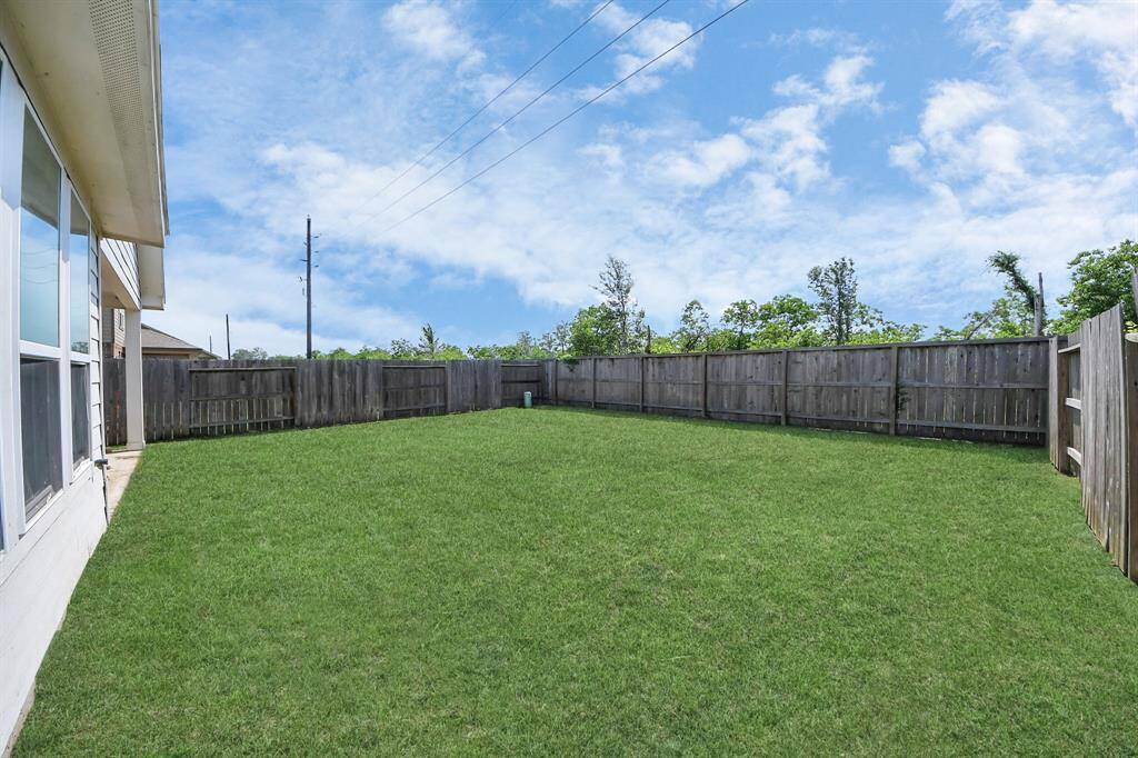 Spacious backyard with well-maintained grass, enclosed by a wooden fence, offering privacy and ample space for outdoor activities.