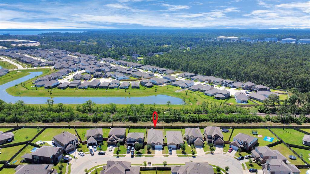 This aerial photo showcases a suburban neighborhood with neatly arranged houses, surrounded by lush greenery and a small body of water. It highlights a tranquil, spacious setting, ideal for families seeking a serene residential area.