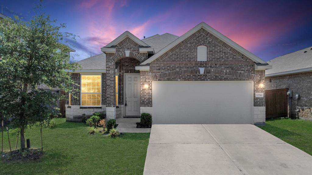 This charming single-story brick home features a well-maintained front lawn, a spacious two-car garage, and a welcoming entrance with elegant archways. The warm exterior lighting complements the beautiful sunset backdrop.