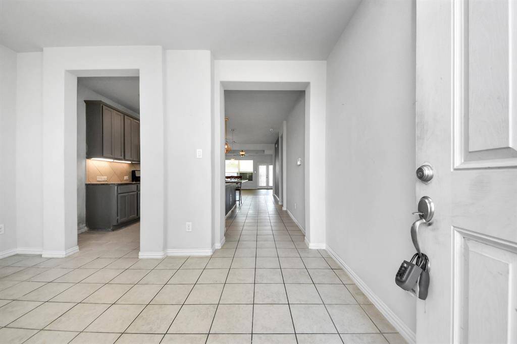 Bright entryway with tiled flooring leading to an open-plan kitchen and living area. Neutral tones and clean lines create a welcoming and spacious feel.