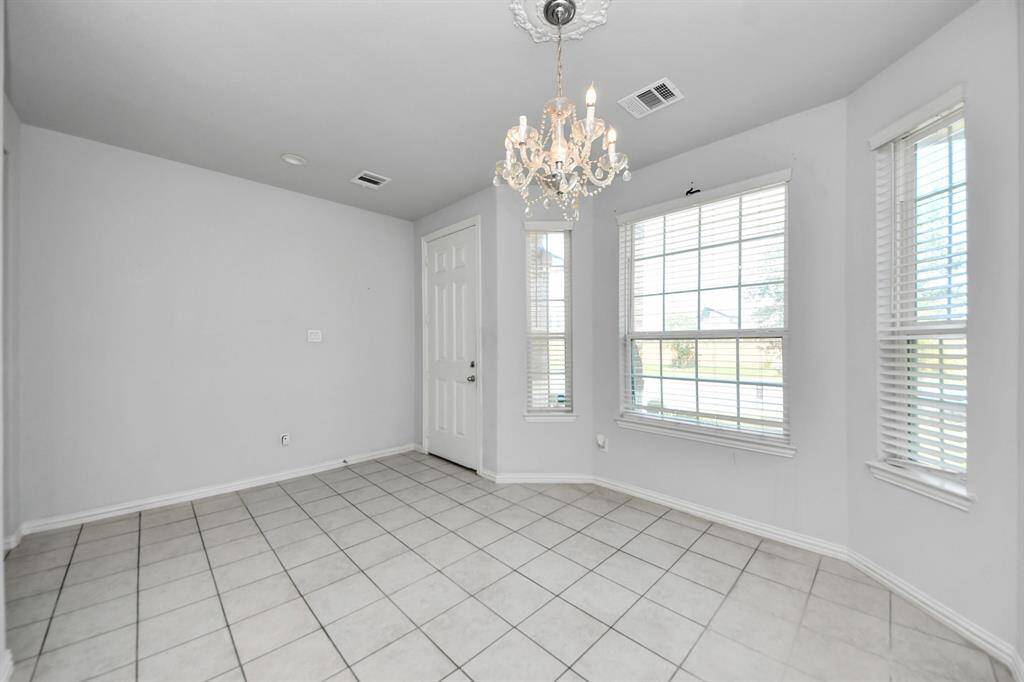 Bright dining area with tile flooring, a decorative chandelier, and large windows offering plenty of natural light.