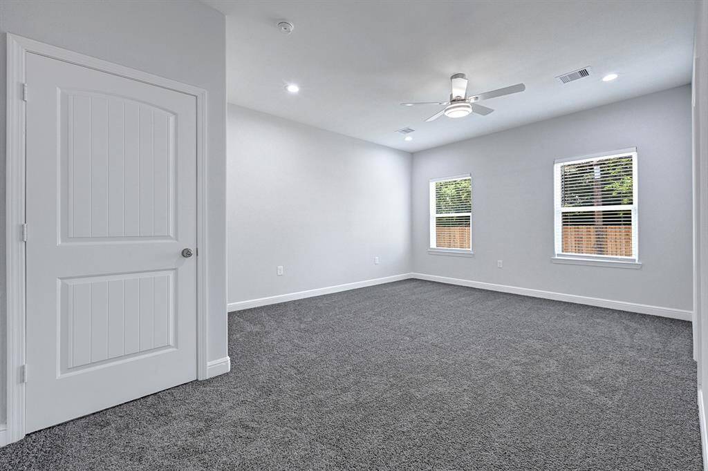 Spacious primary suite with plush carpeting and natural light.
