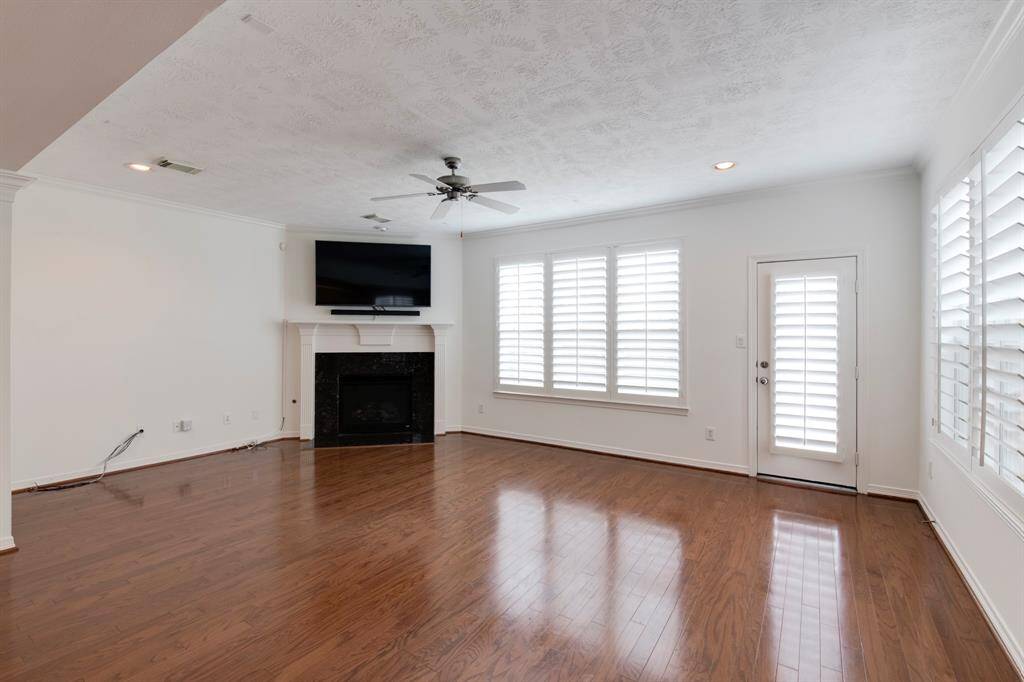 Living room has wood floors, recessed lighting, plantation shutters, ceiling fan and gas log fireplace with mantle. Door leads to the private backyard.