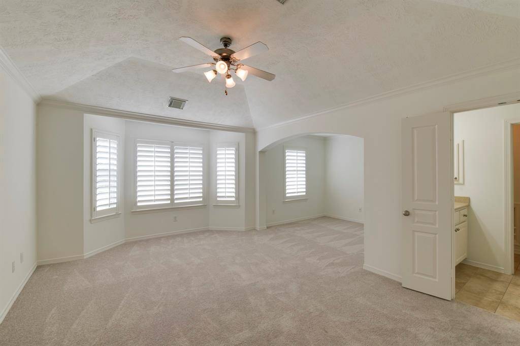 Primary bedroom suite has raised ceiling, new paint (2025), new carpet (2025) an plantation shutters.