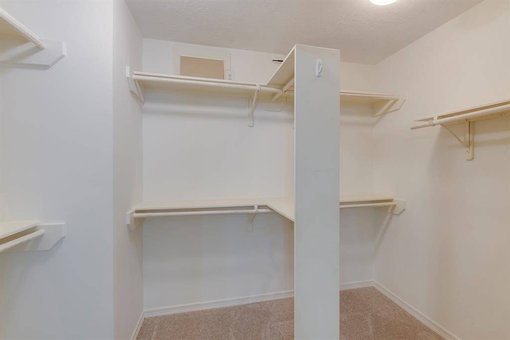 Primary bedroom walk-in closet with plenty of hanging rods and shelves.