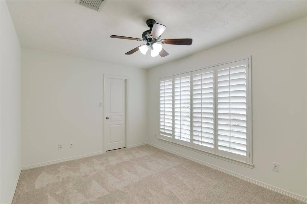 Spacious secondary bedroom has new paint (2025), new carpet (2025), plantation shutters, and ceiling fan.