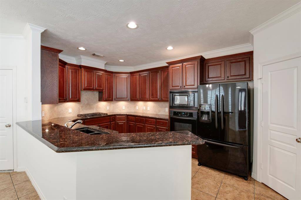 Kitchen has expansive granite countertops, plenty of cabinet storage. Walk-in pantry to the right.