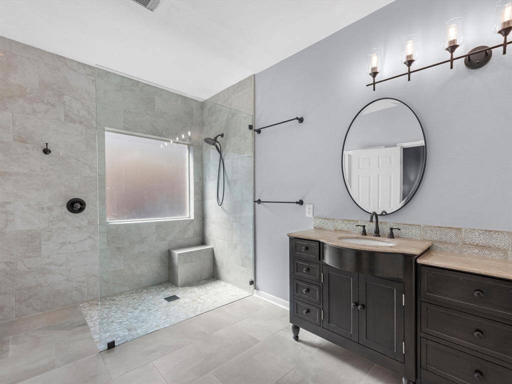 This fantastic walk in shower has frameless glass and bench. it's tiled to the ceiling for a very modern look. Truly a beautiful bathroom!