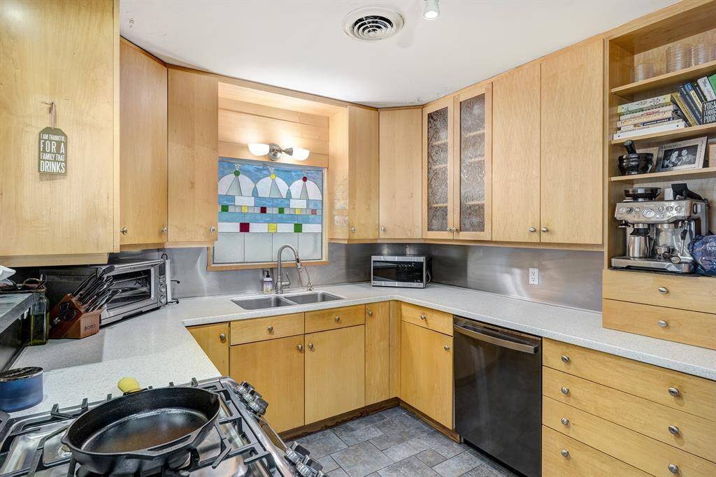 The kitchen has modern blond wood cabinetry and granite counters and a gas range.