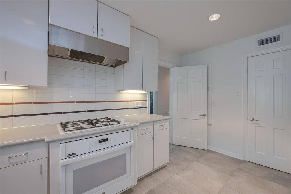Nice  kitchen with sleek white cabinets and countertops, featuring a double sink and built-in gas stove. Bright and spacious with ample storage.