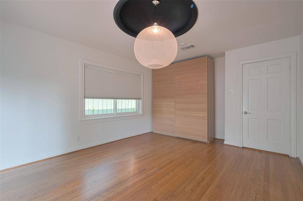 The Primary room features hardwood flooring, a modern light fixture, and ample natural light through a large window. With views to the  patio area, offering a seamless indoor-outdoor flow.