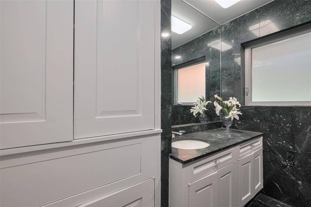 This bathroom features elegant green marble tiles throughout, with a sleek bathtub.