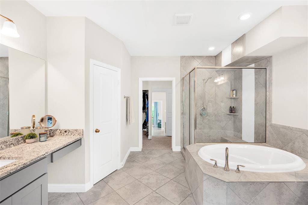 A spa-like primary bathroom with dual vanities, a deep soaking tub, and a large walk-in shower, offering both comfort and style.
