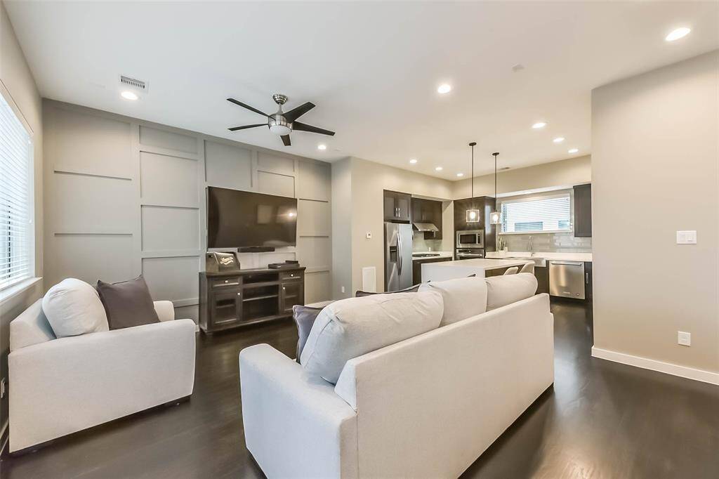 This open-concept living spacefeatures a stylish kitchen withdark cabinetry, quartzcountertops, a sleek island witha built-in wine fridge, andmodern pendant lighting. Thespacious living and dining areasboast elegant fixtures, recessedlighting, and large windows fornatural light. A neutral colorpalette, dark hardwood floors,and contemporary designelements create a sophisticatedyet cozy atmosphere, perfect forentertaining or relaxing.