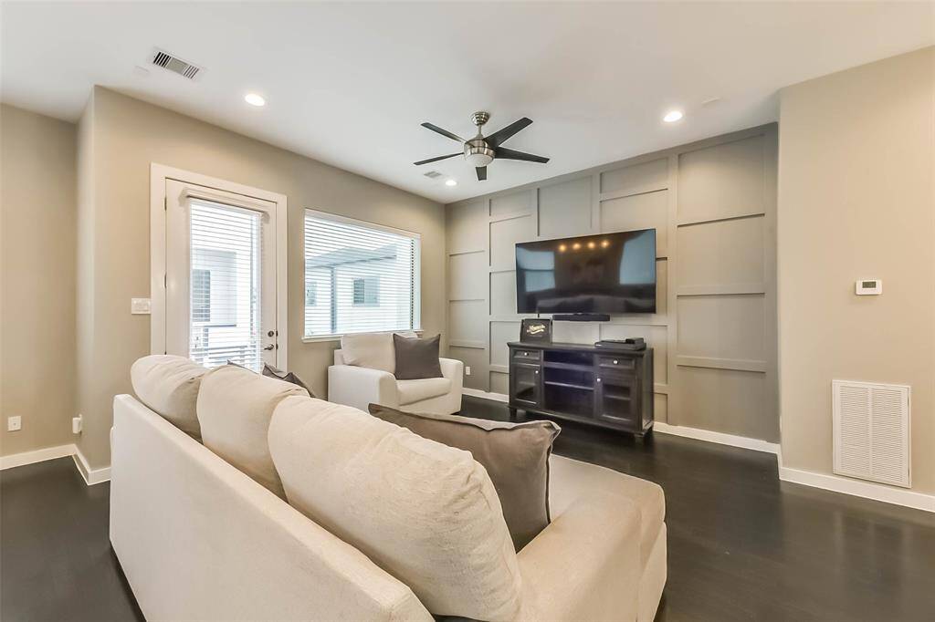 This open-concept living spacefeatures a stylish kitchen withdark cabinetry, quartzcountertops, a sleek island witha built-in wine fridge, andmodern pendant lighting. Thespacious living and dining areasboast elegant fixtures, recessedlighting, and large windows fornatural light. A neutral colorpalette, dark hardwood floors,and contemporary designelements create a sophisticatedyet cozy atmosphere, perfect forentertaining or relaxing.