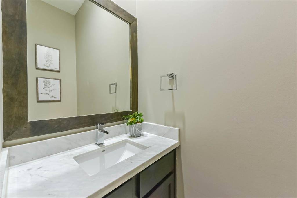 This stylish half bath features asleek marble vanity with amodern undermount sink andcontemporary chrome faucet. Arustic wood-framed mirror addswarmth, complementing theneutral walls and dark cabinetry.Thoughtful touches like a plushtowel, soap dispenser, and asmall succulent create awelcoming feel. Perfectly locatedoff the living room, this spaceoffers convenience and elegancefor guests.