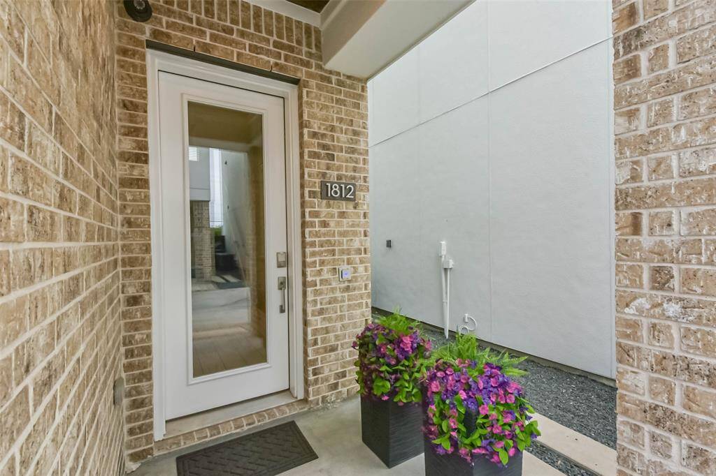 This inviting entryway features astylish brick facade, a modernglass-paneled front door, andelegant planters filled withvibrant flowers. A rich woodpaneled ceiling adds warmth,while the covered entranceprovides a welcoming touch. Thehome’s address is prominentlydisplayed, enhancing curbappeal. A security camera andsmart lock add convenience andpeace of mind. This thoughtfullydesigned entrance sets the tonefor the home's modern charm.