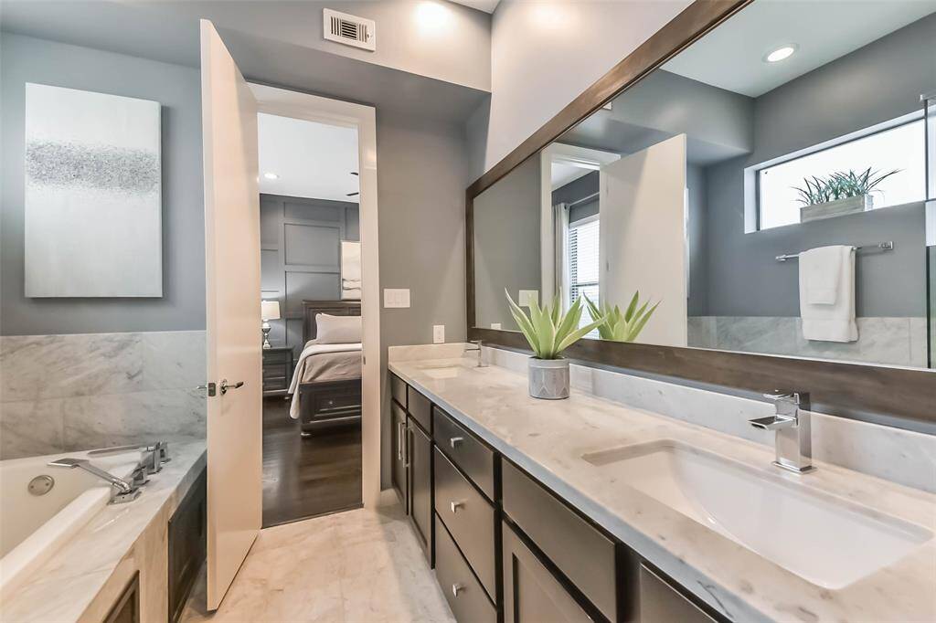 This luxurious master bathroomfeatures a sleek double vanitywith marble countertops, a largeframed mirror, and modernfixtures. The spa-like walk-inshower is enclosed in glass andadorned with elegant marble tile.Soft gray walls complement theclean white finishes, creating asophisticated and tranquilretreat. Thoughtful design andhigh-end details make this spaceboth functional and stylish.