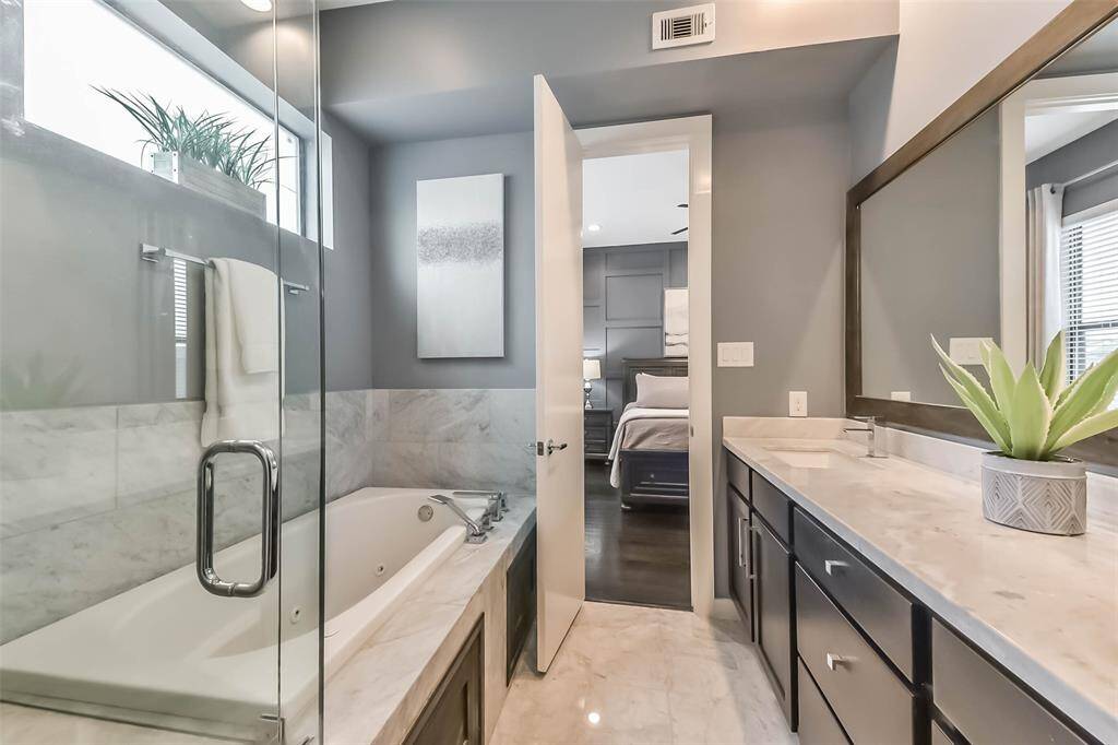 This luxurious master bathroomfeatures a sleek double vanitywith marble countertops, a largeframed mirror, and modernfixtures. The spa-like walk-inshower is enclosed in glass andadorned with elegant marble tile.Soft gray walls complement theclean white finishes, creating asophisticated and tranquilretreat. Thoughtful design andhigh-end details make this spaceboth functional and stylish.