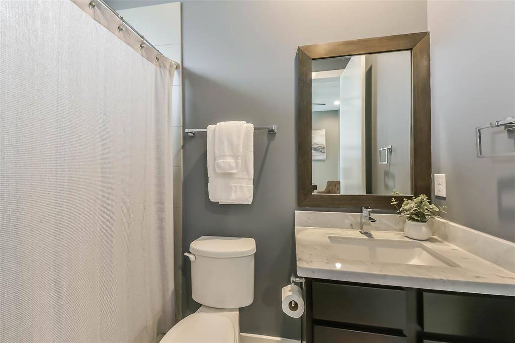 This en-suite bathroom offersmodern finishes, featuring asleek vanity with a marblecountertop, a framed mirror, andstylish fixtures. The combinationbathtub and shower is enclosedwith a neutral-toned curtain forprivacy. Large floor tiles and asoft color palette enhance thespace, creating a clean andinviting atmosphere.Conveniently connected to thesecondary bedroom, thisbathroom is perfect for guests oradditional household members.