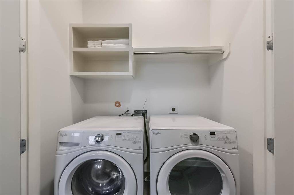 This laundry area offers afunctional and efficient spacewith a front-loading washer anddryer. The white walls andcabinetry create a clean, brightatmosphere, while the darkhardwood flooring contrastsbeautifully with the sleek tileplatform. Conveniently located,this space is designed for easyaccess and practicality.