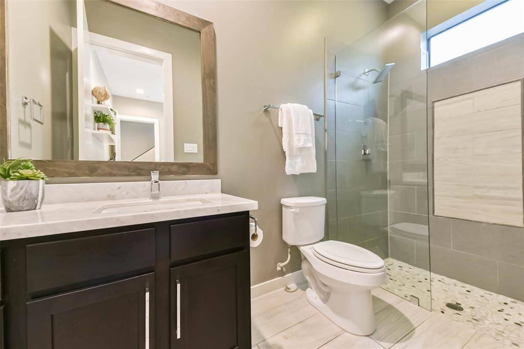 This en-suite first-floor bathroomfeatures a modern design with aspacious glass-enclosed walk-inshower, sleek tilework, andcontemporary fixtures. Thevanity offers ample storage witha marble countertop and a largeframed mirror. Neutral tones andquality finishes create a stylishand functional space.