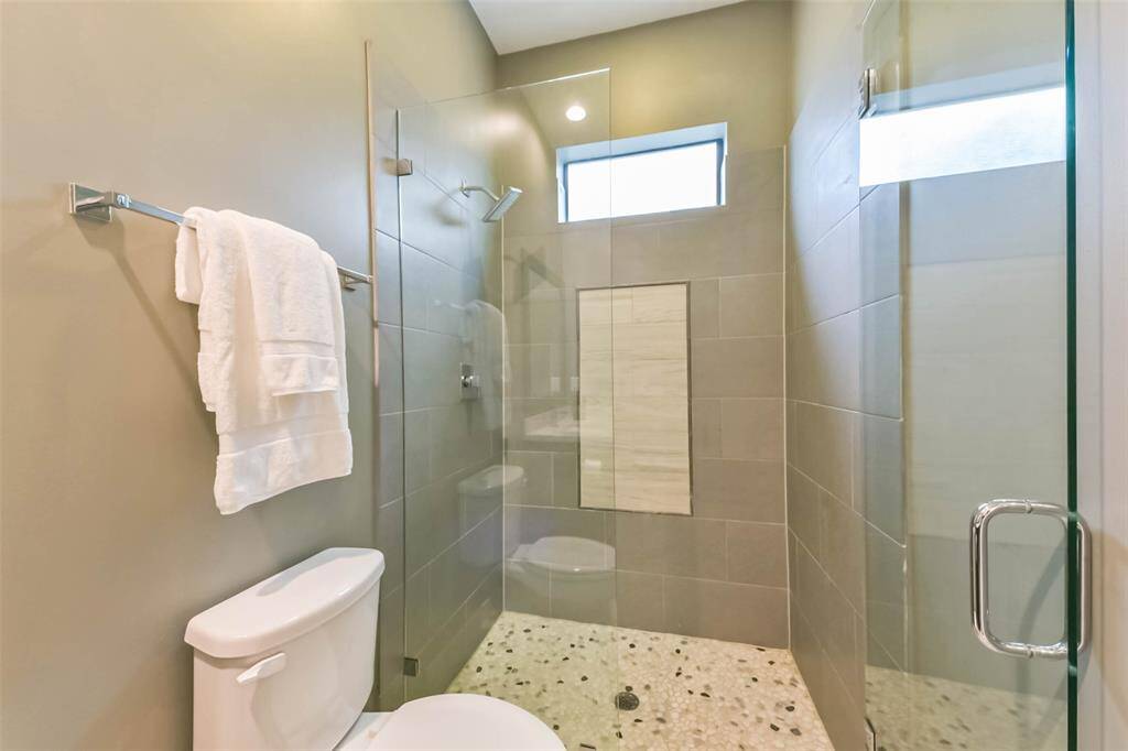 This en-suite first-floor bathroomfeatures a modern design with aspacious glass-enclosed walk-inshower, sleek tilework, andcontemporary fixtures. Thevanity offers ample storage witha marble countertop and a largeframed mirror. Neutral tones andquality finishes create a stylishand functional space.