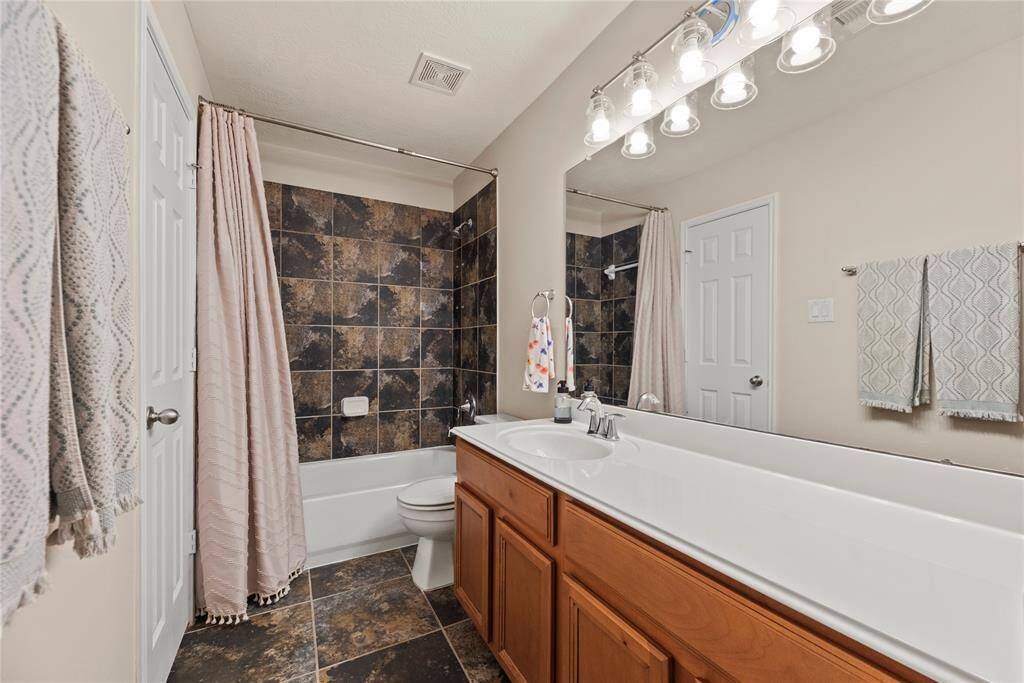 Full guest bathroom with a large vanity and tub/shower combination.