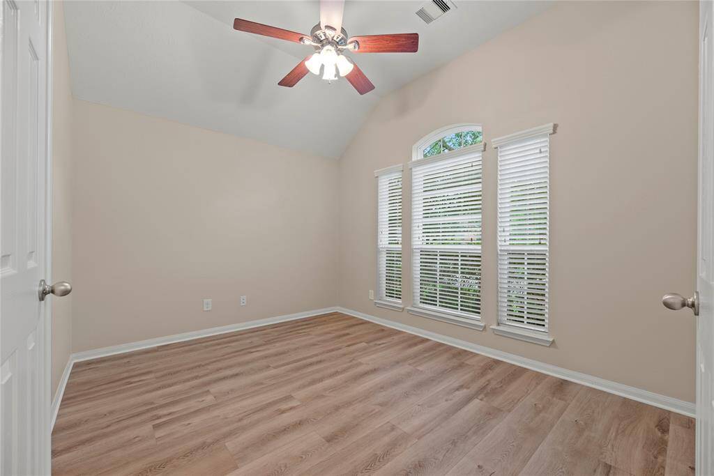 The home office boasts LVP flooring, high ceiling, ceiling fan and double doors for privacy.