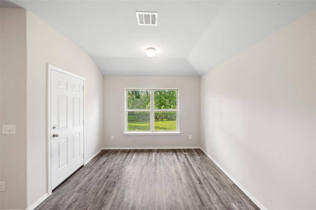 Fully fenced and spacious, lush green backyard bordered by a black metal fence, with a serene wooded area beyond, offering privacy and a natural backdrop.