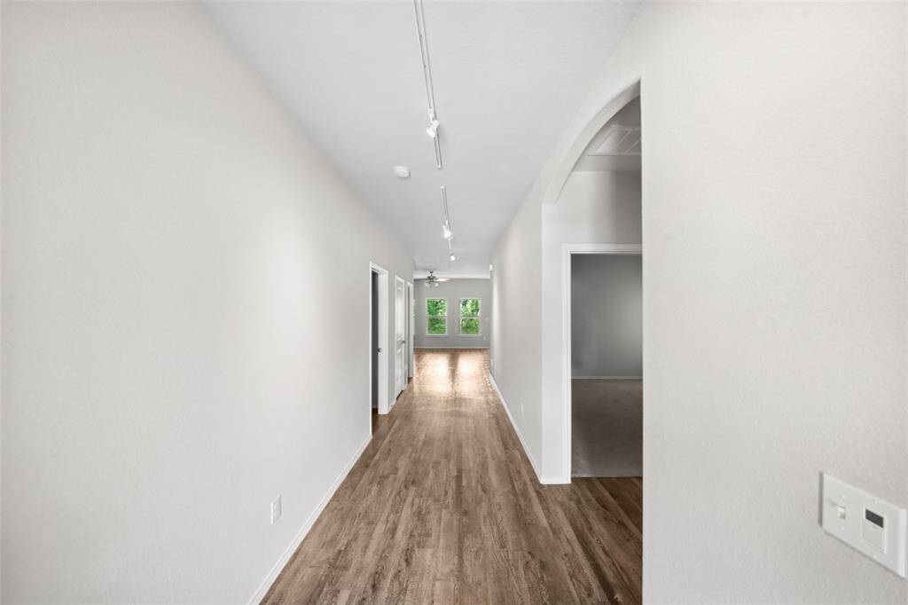 Modern kitchen with a spacious white island, stainless steel appliances, and sleek cabinetry. Features wood flooring and ample overhead lighting, creating a bright and inviting space.