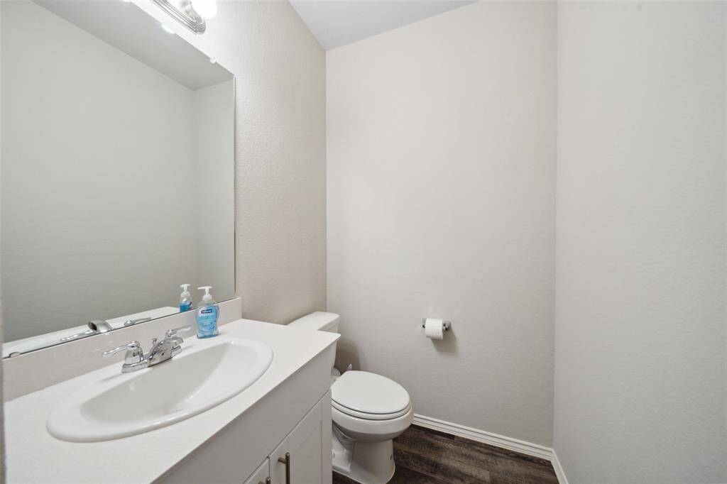 Bright, spacious living area with wood flooring, neutral walls, and ample natural light from multiple windows. Ceiling fan and recessed lighting enhance the modern feel. Suitable for comfortable living and entertaining.