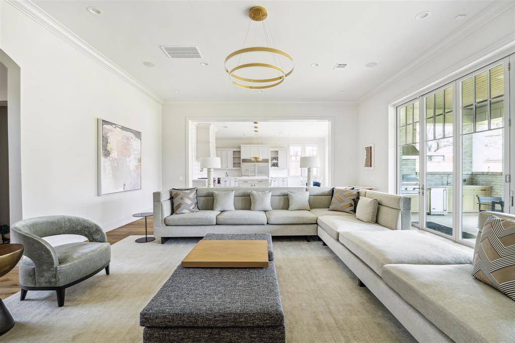 Reentering the family room, we see how well-designed the space is for seamless indoor-outdoor living with an open-concept layout and floor-to-ceiling sliding glass doors that extend to the outdoor living area. A striking chandelier, gleaming oak hardwood floors, and soaring 12-foot ceilings enhance the room’s elegance and airy ambiance.