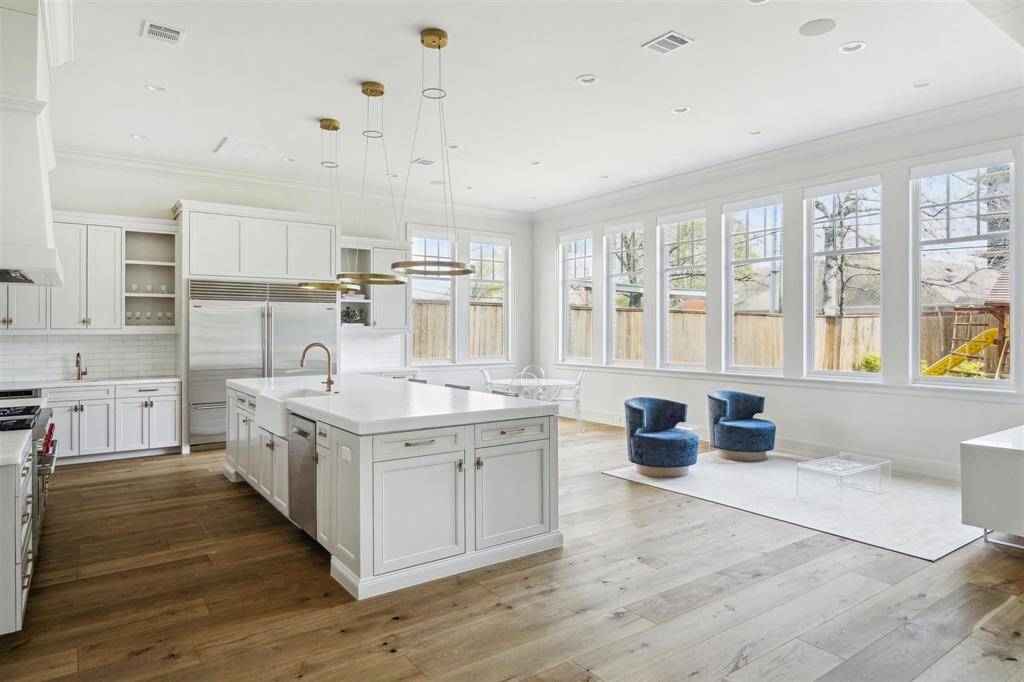 A culinary masterpiece, this gourmet kitchen features a striking Opal White Marble island that flows effortlessly into the breakfast nook. Designed with both style and function in mind, it boasts top-of-the-line appliances, including a state-of-the-art Wolf oven. The eye-catching Bianco Dolomite marble backsplash and custom vent hood seamlessly complement the elegant neutral-tone cabinetry, creating a space that is as sophisticated as it is functional.