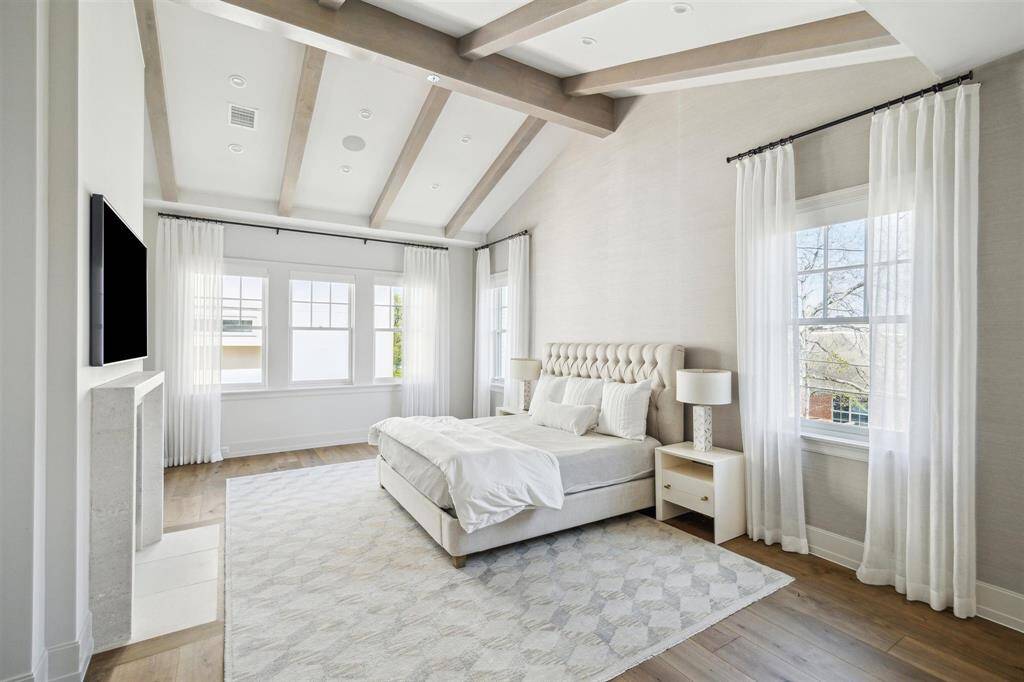 Upstairs, a breathtaking primary suite awaits, featuring gleaming oak hardwood floors and a striking ceiling adorned with white pine beams. This luxurious retreat is centered around an exquisite gas log fireplace with a custom stone mantel and boasts a spa-like marble bath with a spacious walk-in closet.