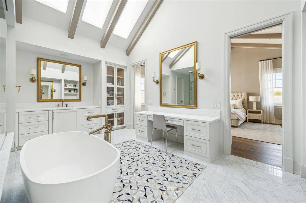 Every detail has been meticulously crafted in this exquisite spa-like bath, featuring a luxurious soaking tub and elegant Carrara marble flooring. Soaring ceilings with striking skylights bathe the space in natural light, creating a serene and tranquil oasis.