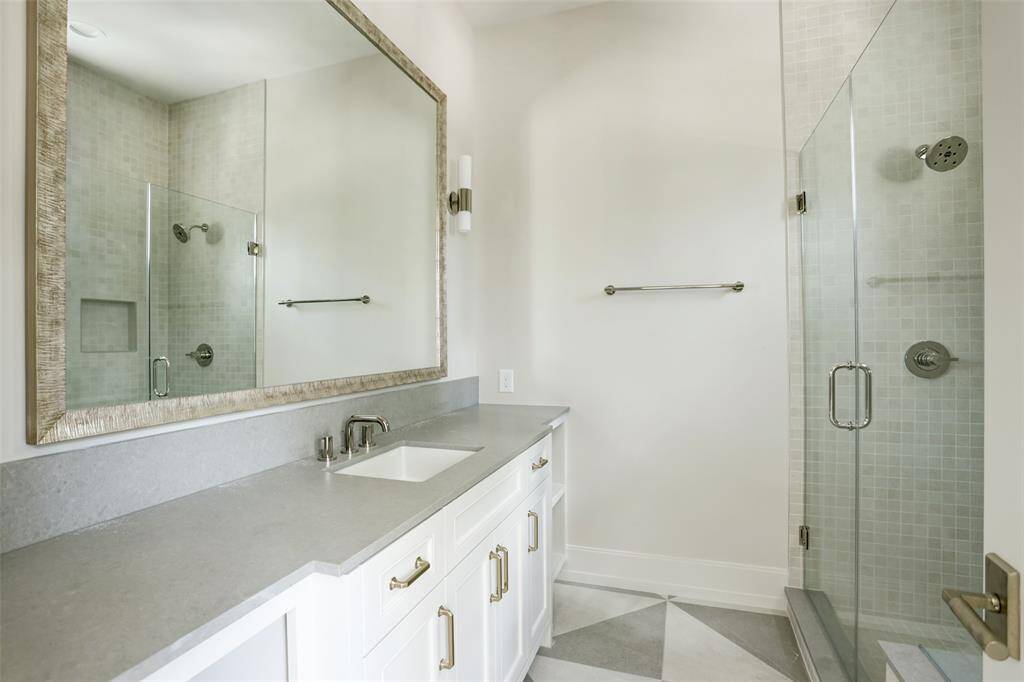 Sleek and refined, this en-suite bath boasts a spacious honed quartz vanity topped with a beautifully framed mirror. A striking glass-enclosed shower completes the space, blending modern design with everyday comfort.