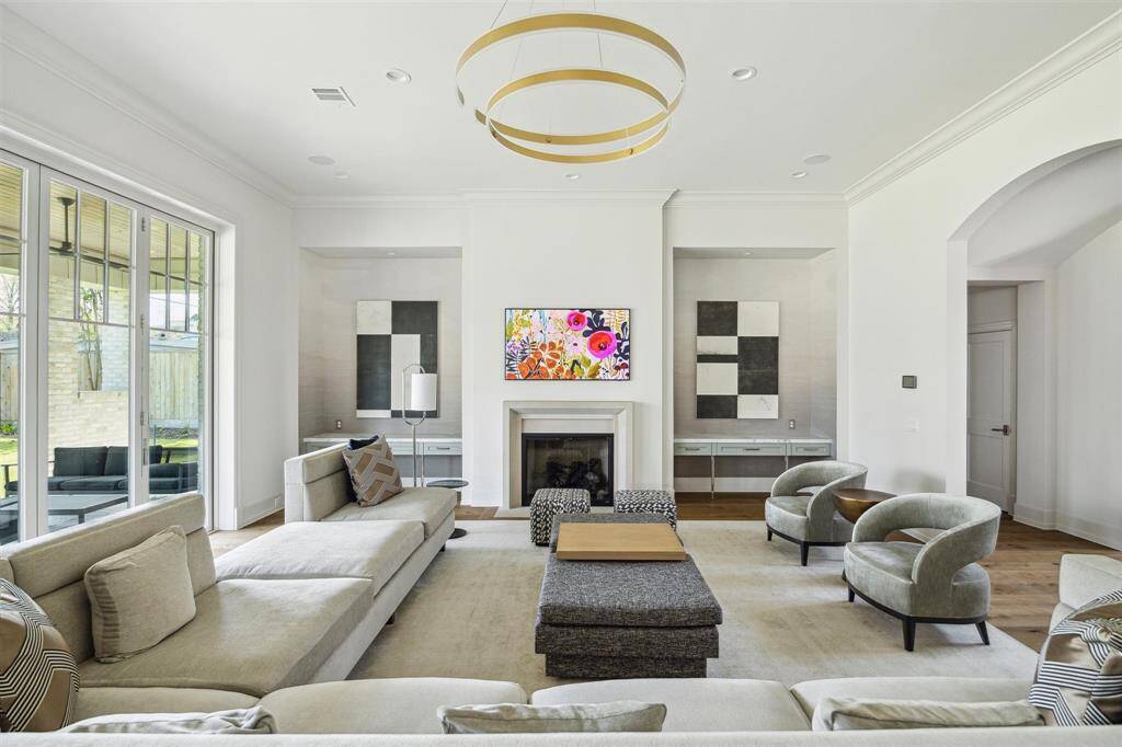 The exquisite family room embodies elegance with soaring 12-foot ceilings and white oak hardwood floors framing a stunning cast stone gas log fireplace. Grand sliding glass doors open seamlessly to the outdoor living space, complete with a summer kitchen, offering the ideal blend of indoor and outdoor living. Thoughtfully curated designer finishes elevate the home’s sophisticated charm throughout.