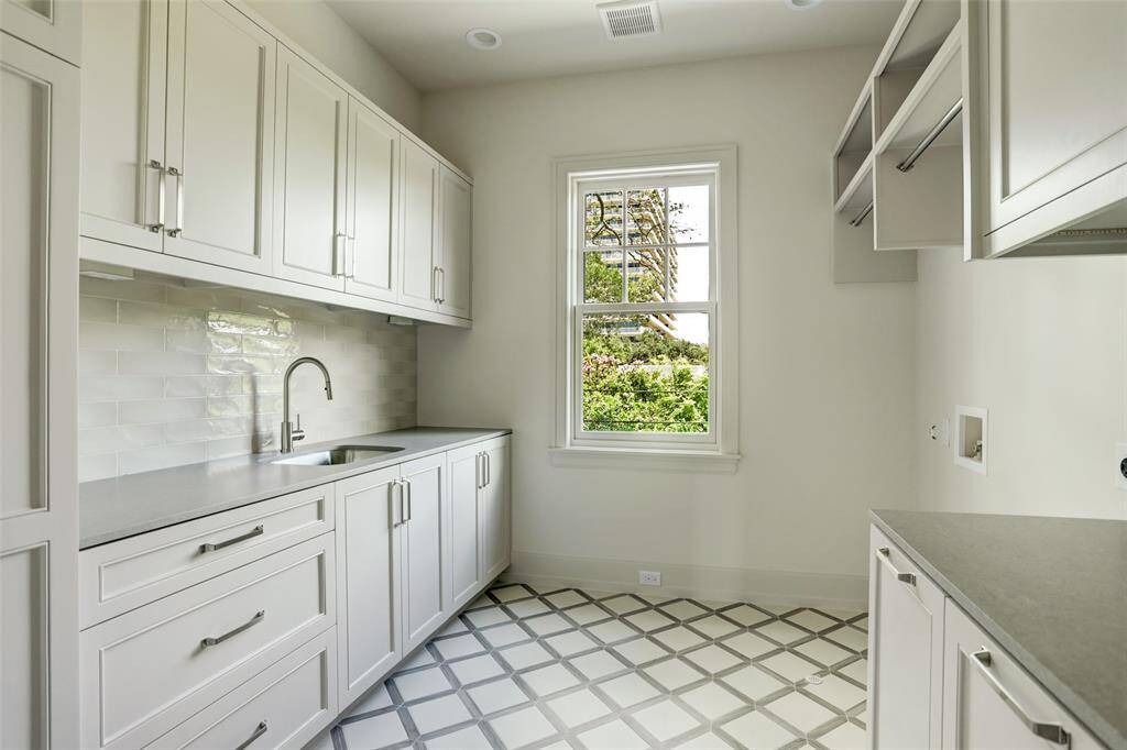 Conveniently situated on the second floor, this impressive utility room features stylish tile flooring, custom cabinetry, and durable honed quartz countertops—combining function with elevated design.