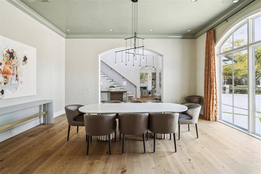 The formal dining room exudes sophistication, framed by a graceful arched cased opening and anchored by an elegant Sonneman Suspenders chandelier. Expansive windows overlook the manicured grounds, filling the space with natural light. It's a stunning, welcoming room that sets the tone as you enter the home.