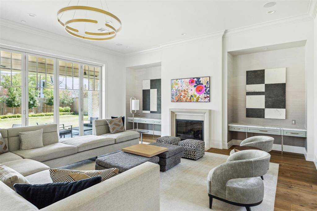 Bathed in natural light, the family room offers refined comfort, centered around a gas log fireplace with a cast stone surround and elegant white oak hardwoods. Expansive sliding glass doors seamlessly connect the space to the stunning outdoor living area.