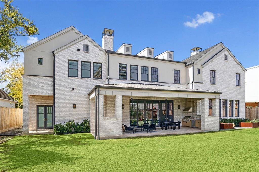 This stunning home showcases a beautifully crafted brick and stucco exterior, elegantly accented by copper lanterns. The covered outdoor pavilion is a true highlight, featuring custom natural stone tiles and a charming wood-paneled ceiling. Perfect for entertaining, the space also boasts an impressive summer kitchen, seamlessly blending luxury and functionality.