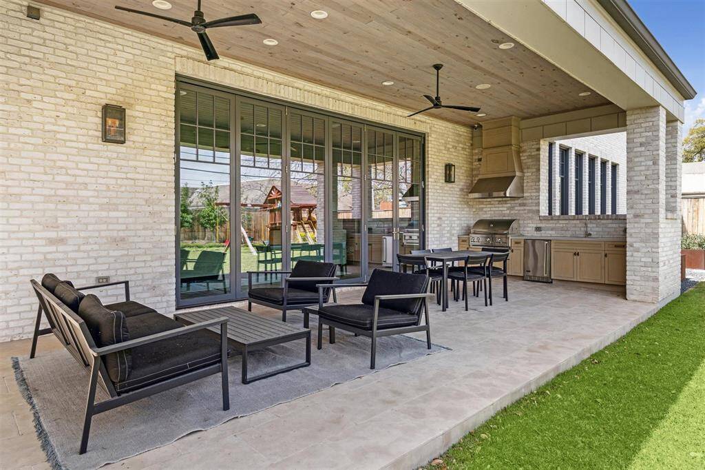Expansive sliding glass doors seamlessly connect the indoors to the summer outdoor kitchen, featuring an Artisan grilling station, a prep sink, and custom cabinetry. This well-appointed space creates the perfect setting for effortless entertaining.