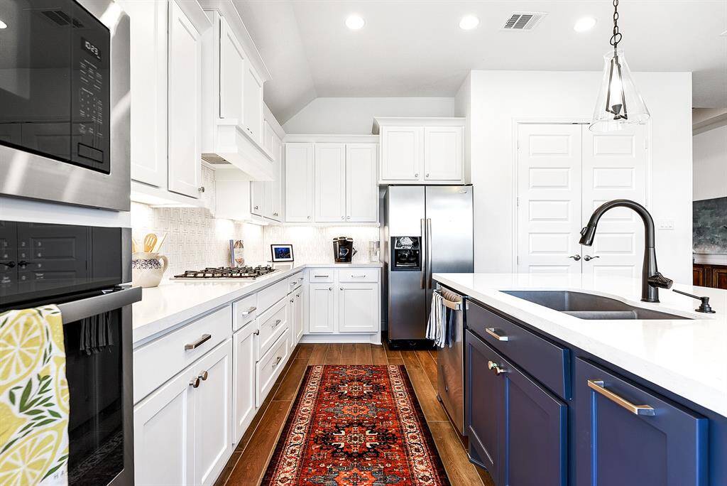 The kitchen offers plenty of counter space for meal preparation, with room for multiple chefs, and cabinets providing ample storage. All cabinetry is complete with hardware, and the kitchen features matching stainless steel appliances, including a gas cooktop, wall oven, and microwave.