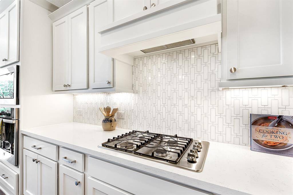 A closer look at the beautiful white custom tile backsplash, complemented by white cabinetry and quartz countertops. The kitchen also features convenient pots and pan drawers for added storage.
